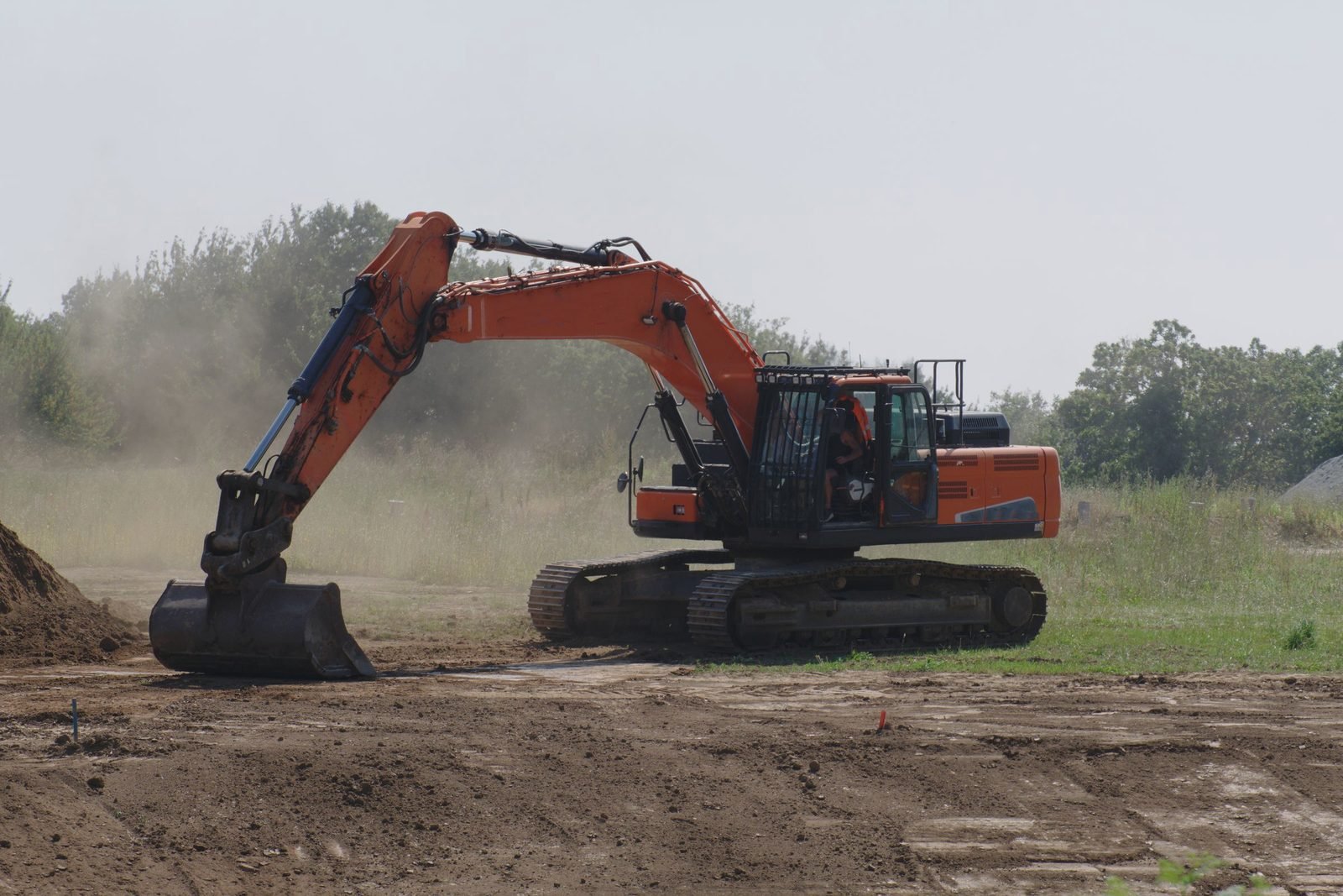 An excavator levels ground on a cleared site.
